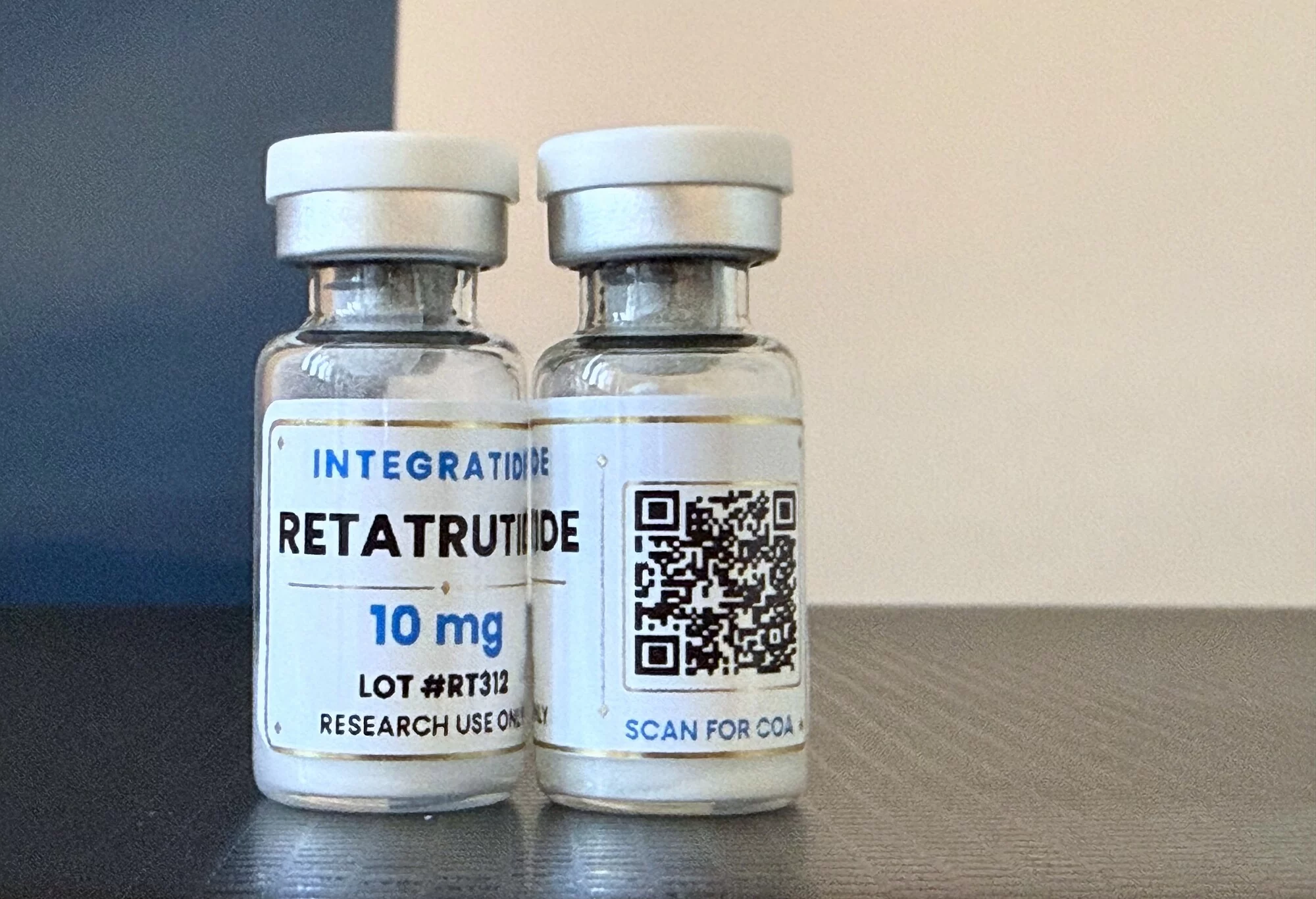 Two Integratide Retatrutide 10 mg vials, the back label showing the scan-for-COA QR code for lot RT312